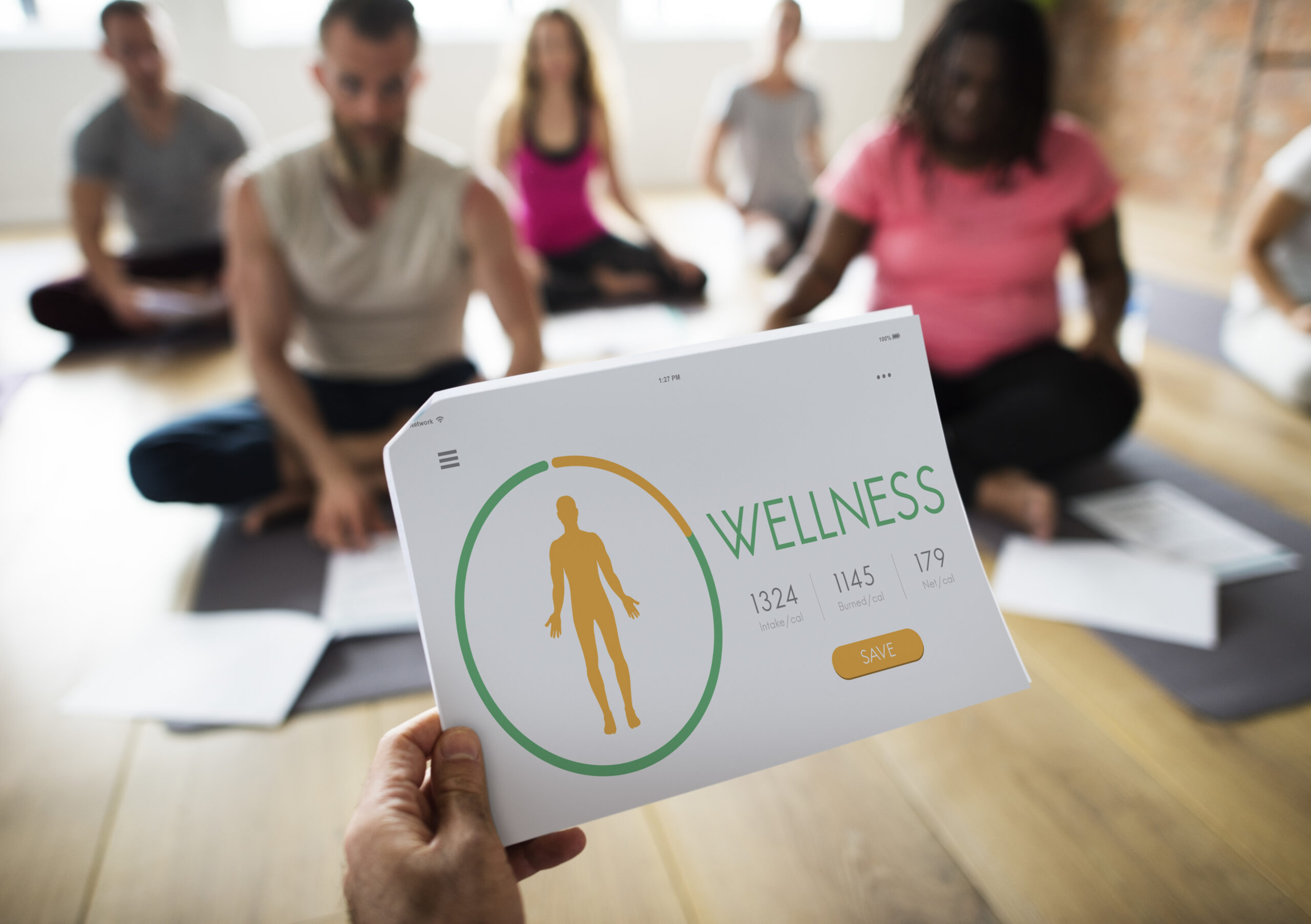 Wellness tracking dashboard held during a fitness class — digital health and wellness concept